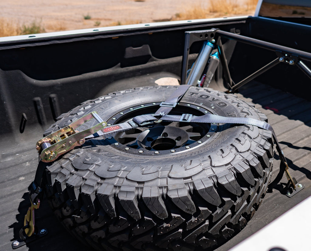display of sdhq built universal spare tire brackets installed in bed of truck with spare tire